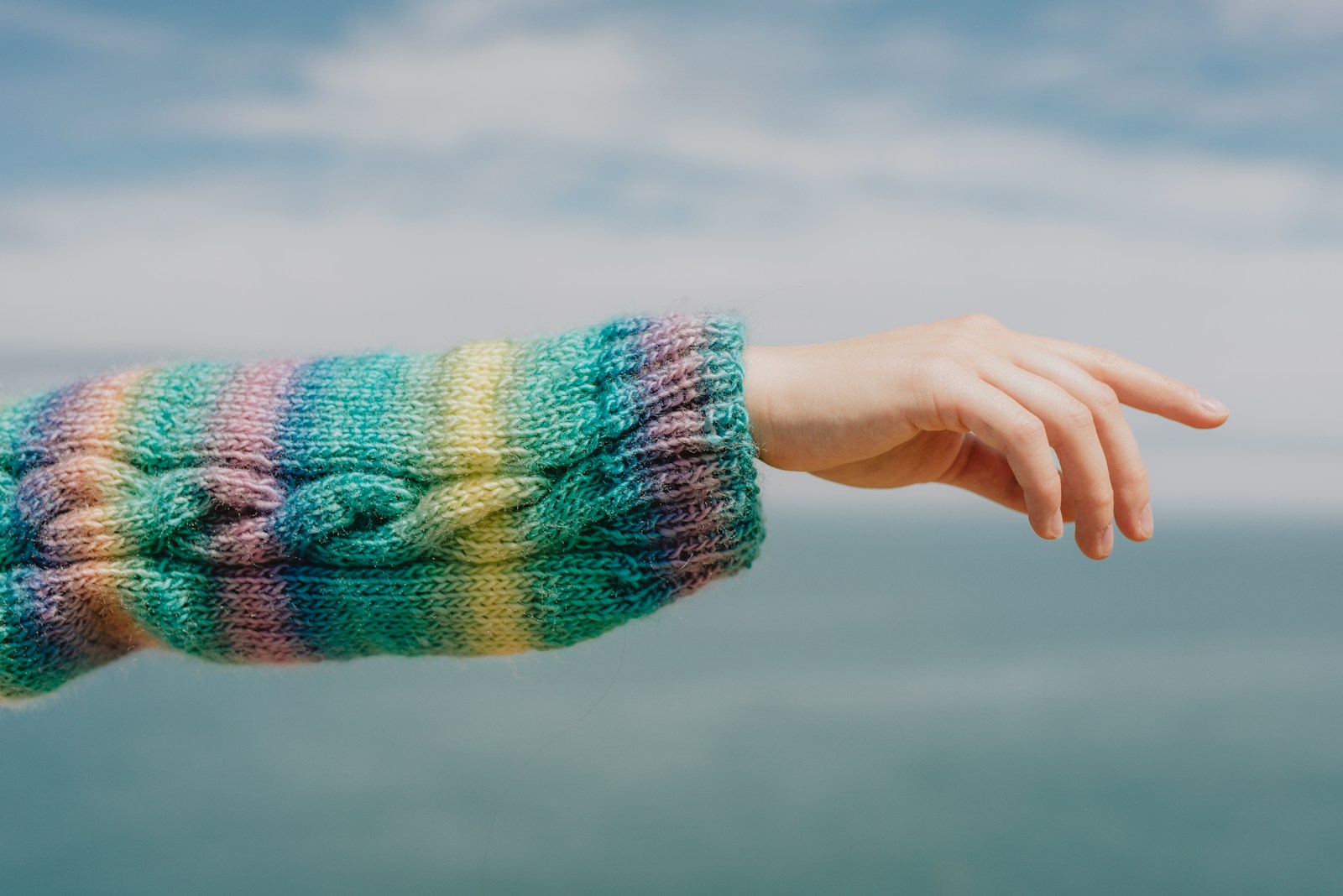 A hand reaches out with a colorful sweater.